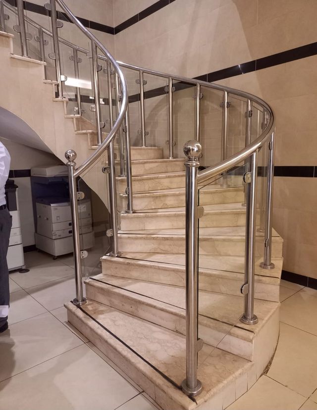 درابزين ستانلس ستيل منحنٍ بزجاج ودرجات رخام